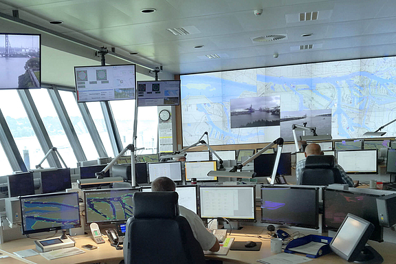 Control Center mit mehreren Arbeitsplätzen, zahlreichen Bildschirmen und Video Wall im Hintergrund