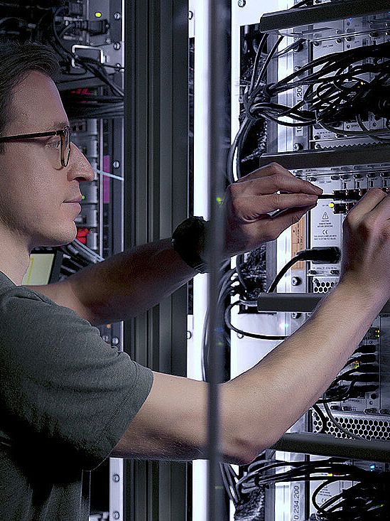 Mann repariert in einem Serverraum Anschlüsse