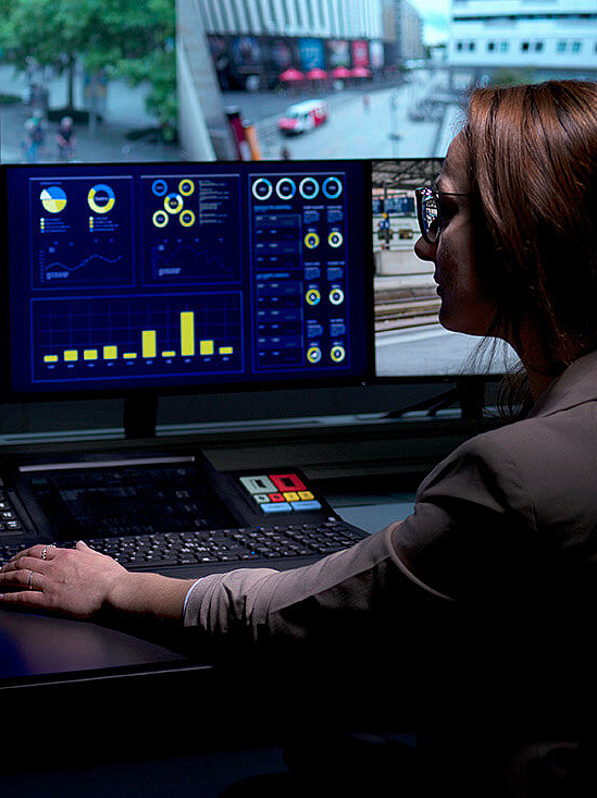 Frau sitzend im Control Room an mehreren Bildschirmen