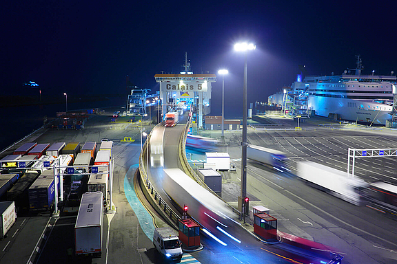 Beleuchteter Hafen mit Container-Transportern bei Nacht 