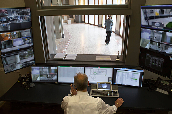 Mann im Control Room mit zahlreichen Bildschirmen zur Ãœberwachung