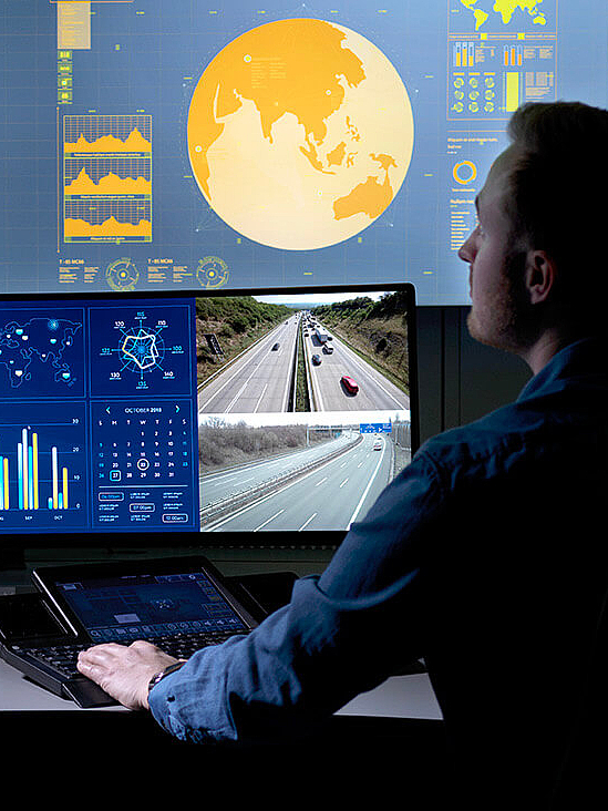  Woman sitting in control room in front of several screens