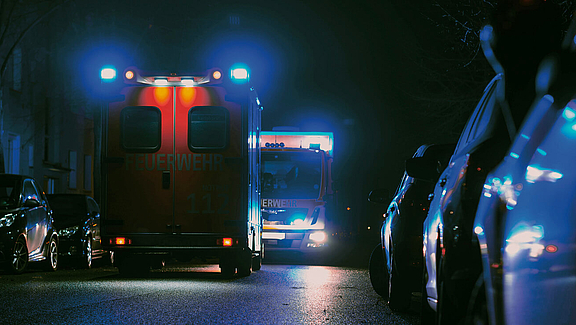 Rettungsfahrzeuge bei Nacht mit blauen Sirenen