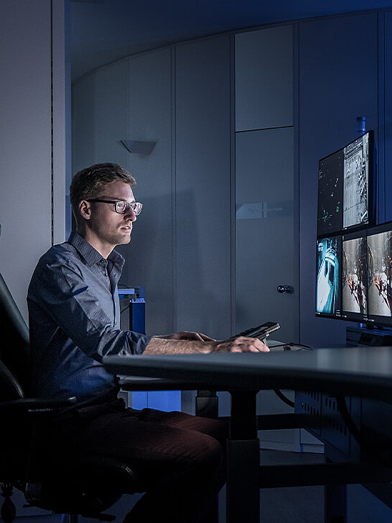 Man sitting in control room in front of several screens