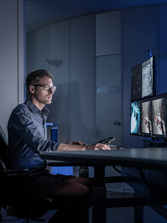 Mann sitzend in Control Room vor mehreren Bildschirmen
