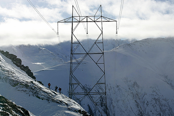 Ein Strommast inmitten schneebedeckter Berge
