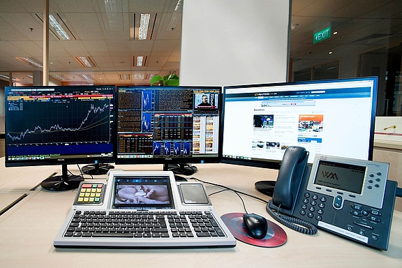 Trading Arbeitsplatz mit Telefon, smartTOUCH Tastatur und mehreren Bildschirmen