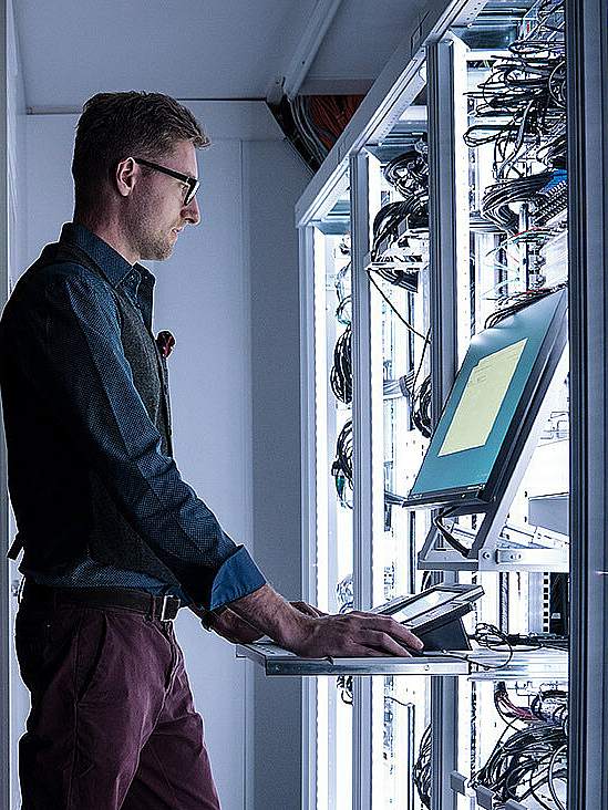 Man working in lighted server room at adminstrator workplace