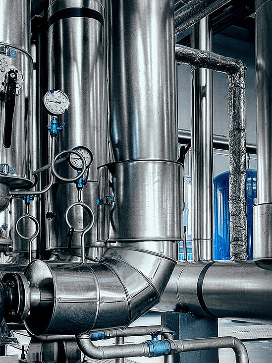 Interior of an energy plant with numerous stainless steel tanks and pipes