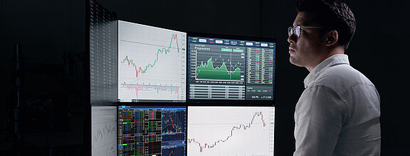 Mann stehend an Trading Arbeitsplatz mit mehreren Bildschirmen