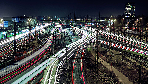 Beleuchtetes Schienennetz bei Nacht an einem Bahnhof