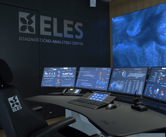 Hochmoderner Arbeitsplatz im Control Room mit mehreren Bildschirmen und Video Wall im Hintergrund
